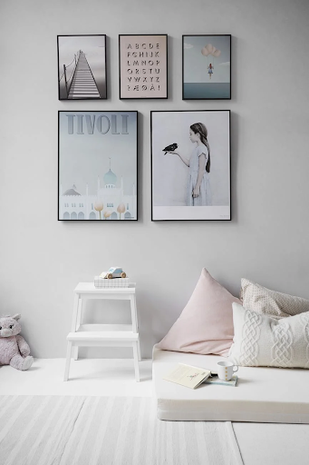 a gallery wall with five framed images in a white bedroom