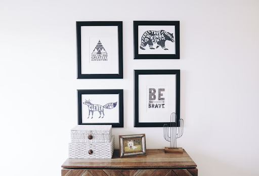 a set of four framed pieces of wall art above a side table